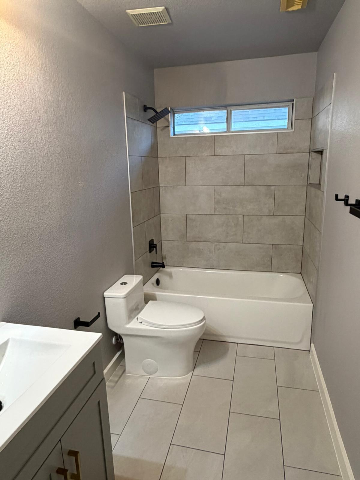 Completed bathroom remodel in Buda TX with new tile tub surround, tile flooring, and updated vanity by B&H Remodeling