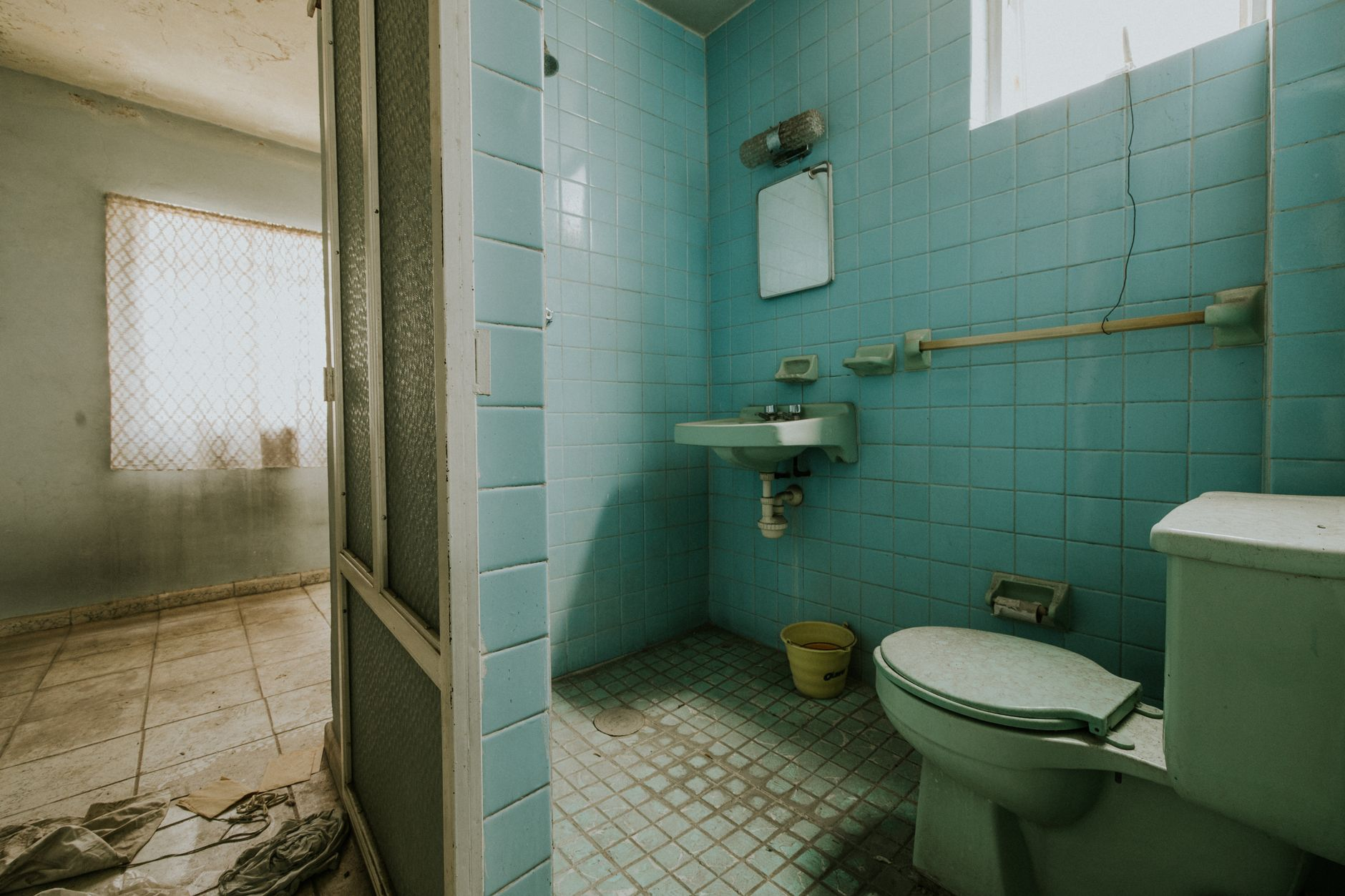 Worn bathroom with old blue tiles and fixtures showing clear signs it needs shower remodeling in Austin or Round Rock TX