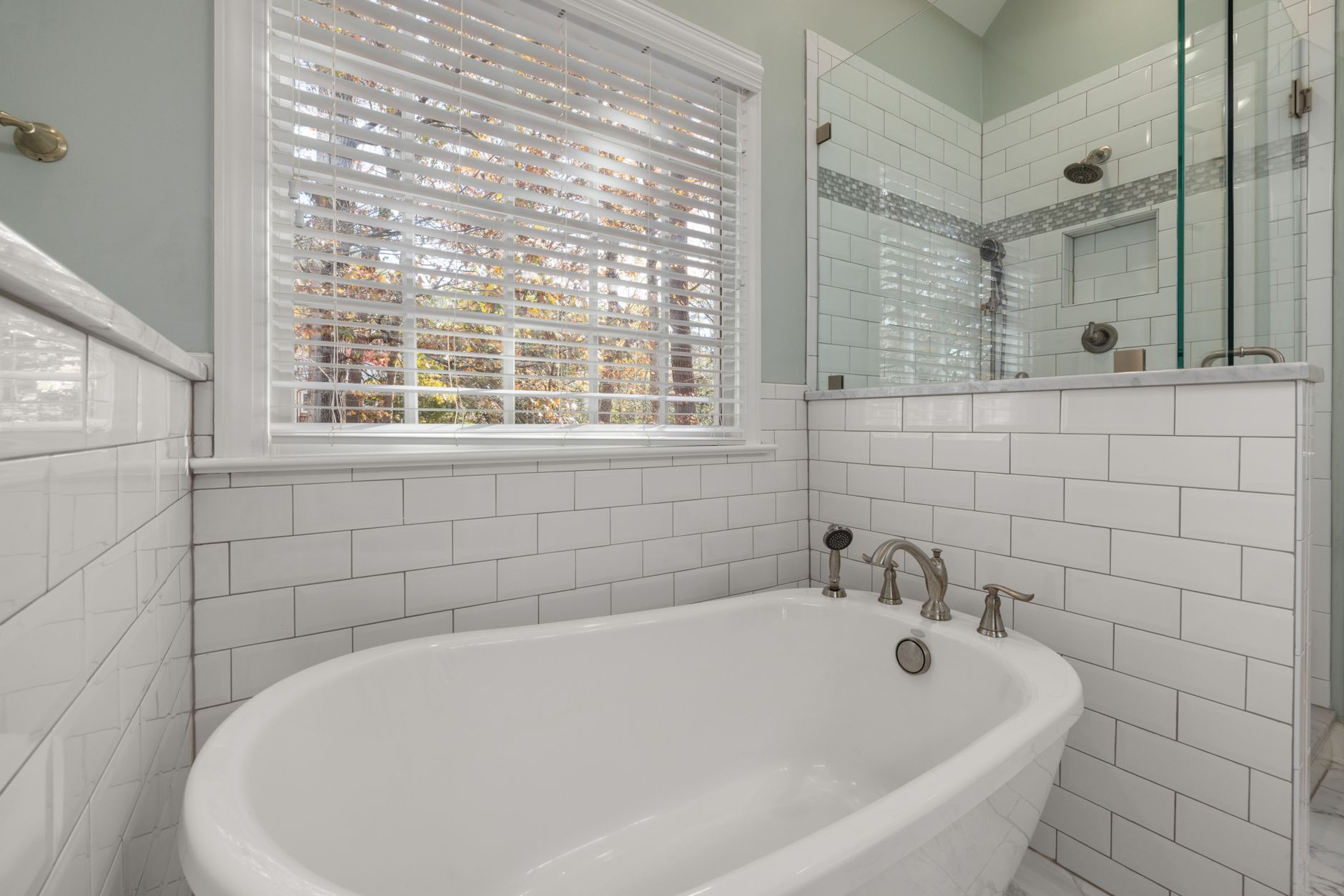 Spacious bathroom remodeling in Austin with freestanding tub and glass subway tile shower by B&H Remodeling