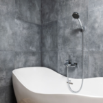 Modern white bathtub replacement in a light gray tiled bathroom by B&H Remodeling serving Austin and Round Rock TX