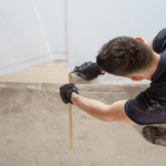 Construction worker measuring and cutting flooring panels during a professional flooring installation project in Austin an…