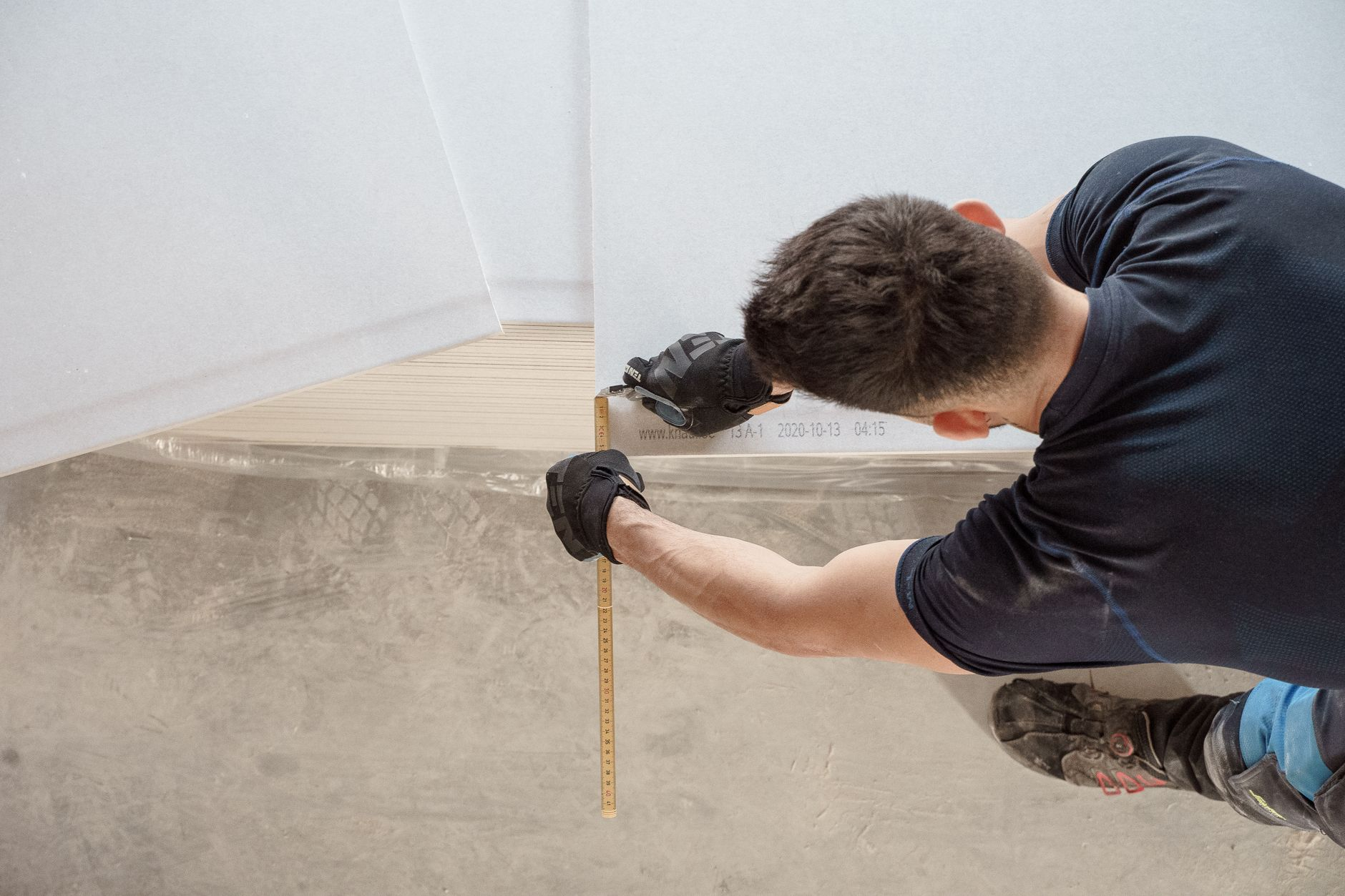 Construction worker measuring and cutting flooring panels during a professional flooring installation project in Austin an…