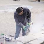Construction worker cutting stone tiles with a power saw during a tile installation project in Austin and Round Rock TX