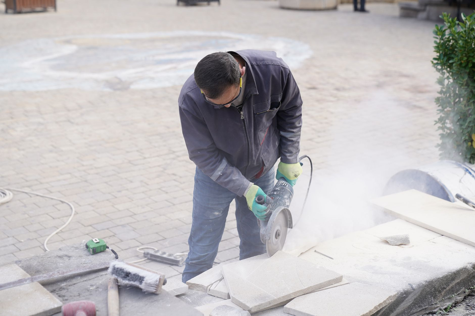 Construction worker cutting stone tiles with a power saw during a tile installation project in Austin and Round Rock TX
