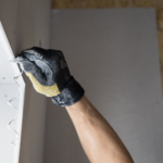 Gloved hand applying plaster for drywall repair, a common approach for Austin and Round Rock homeowners
